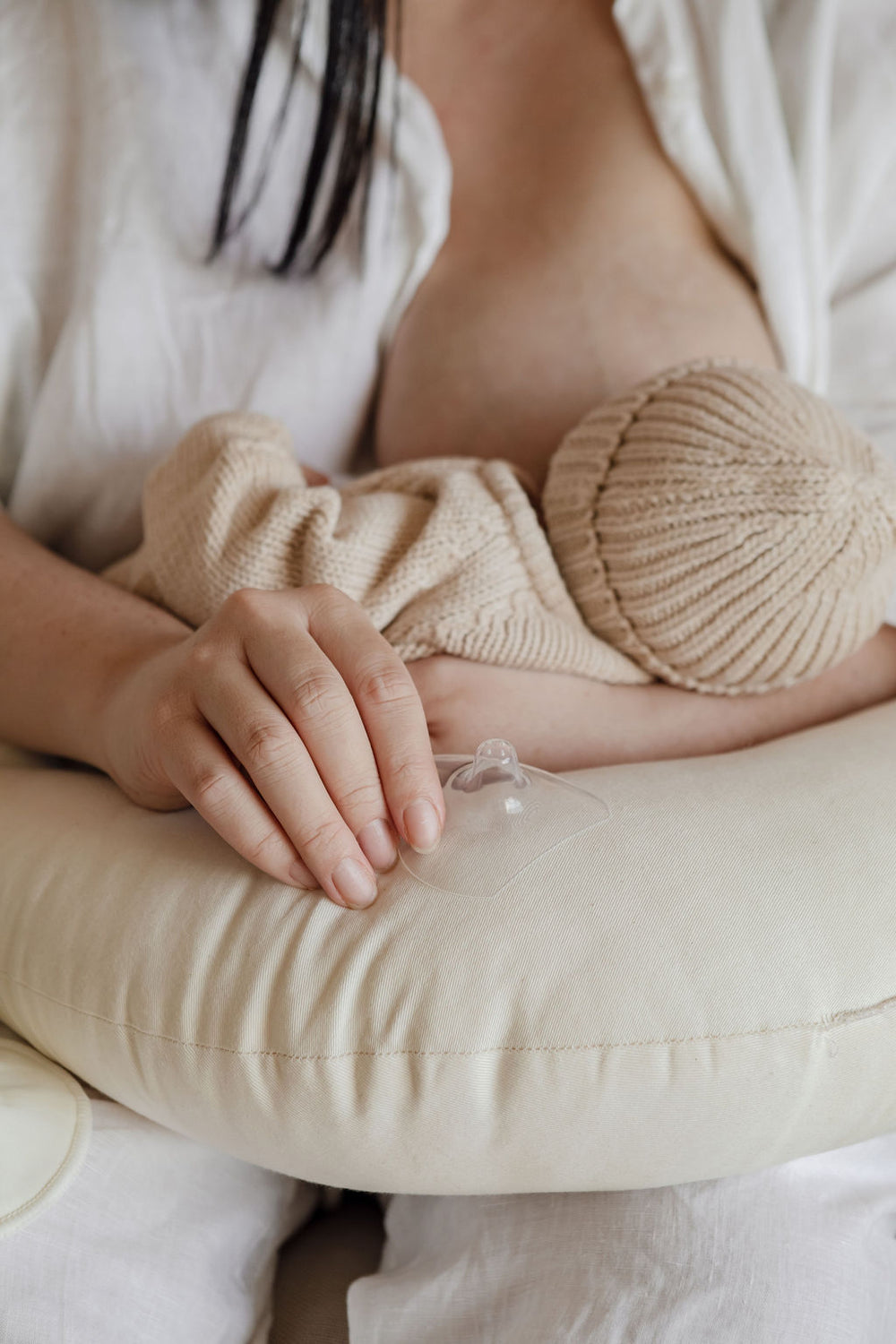 A woman is breastfeeding her baby on a pillow.