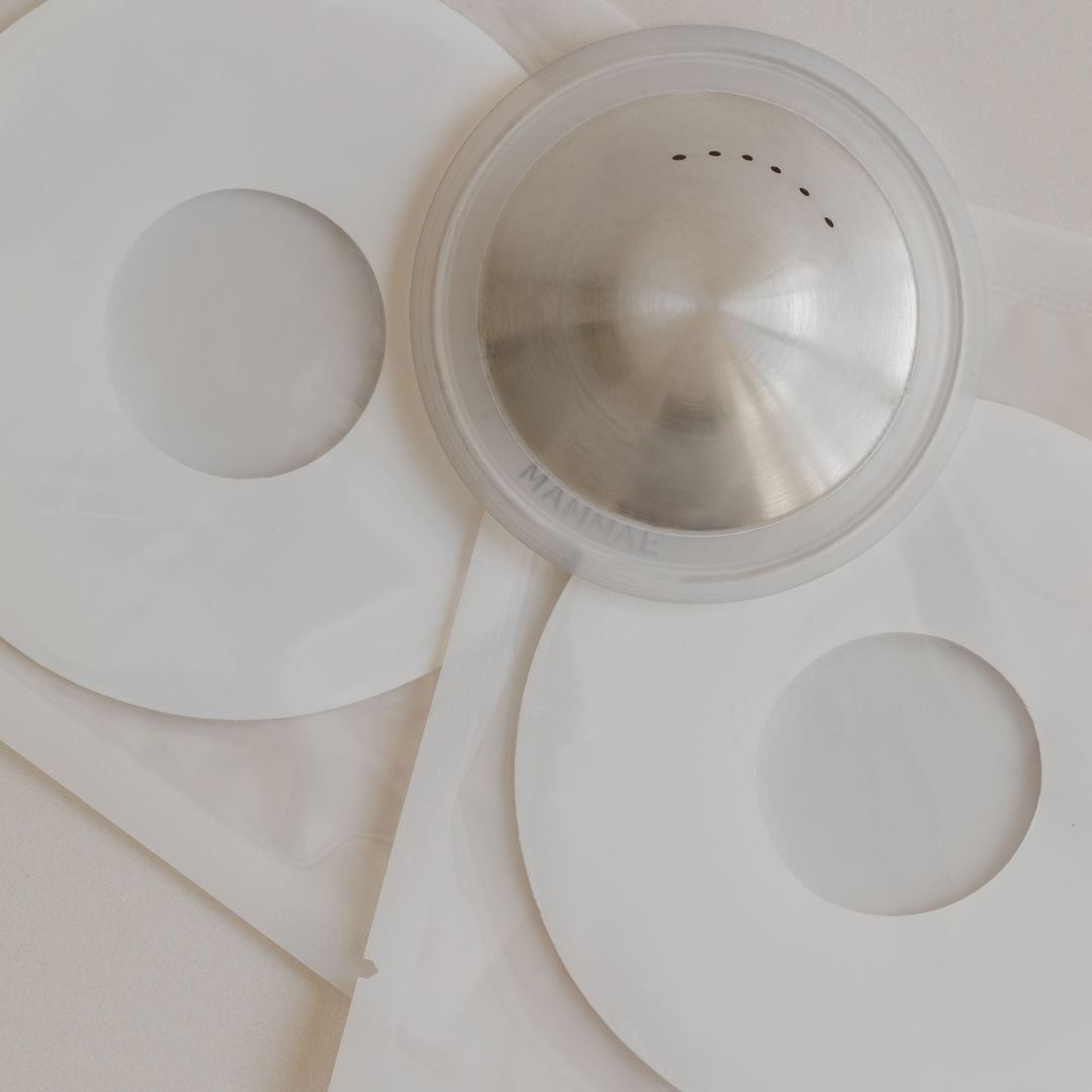 Stainless steel coffee dripper with two white paper filters on a beige surface, ideal for those seeking a solution to nipple damage during breastfeeding. - Mammae silver nipple care bundle