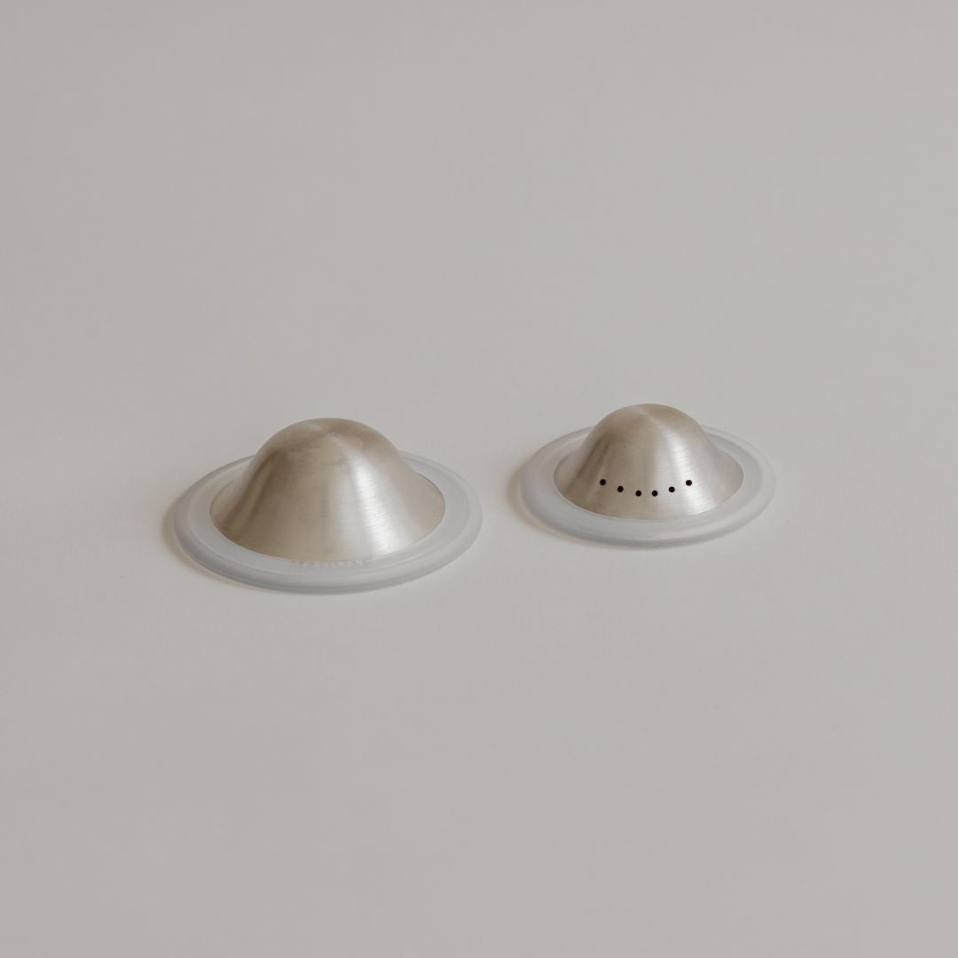 Two fine Mammae silver nipple cups on a white background.