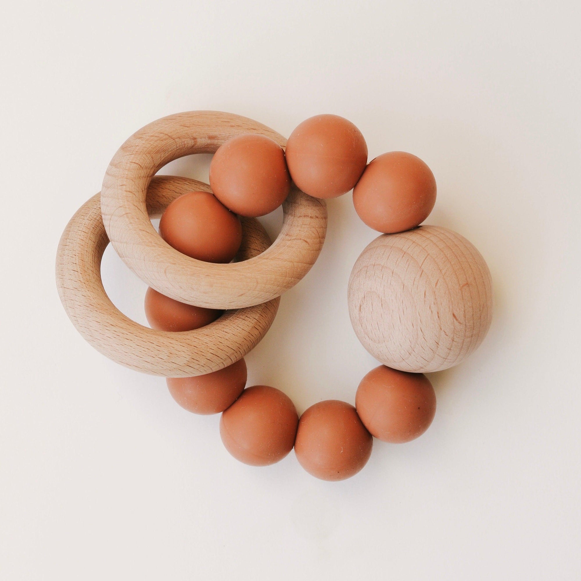 A set of Dove & Dovelet Wooden Silicone Teethers on a white surface.