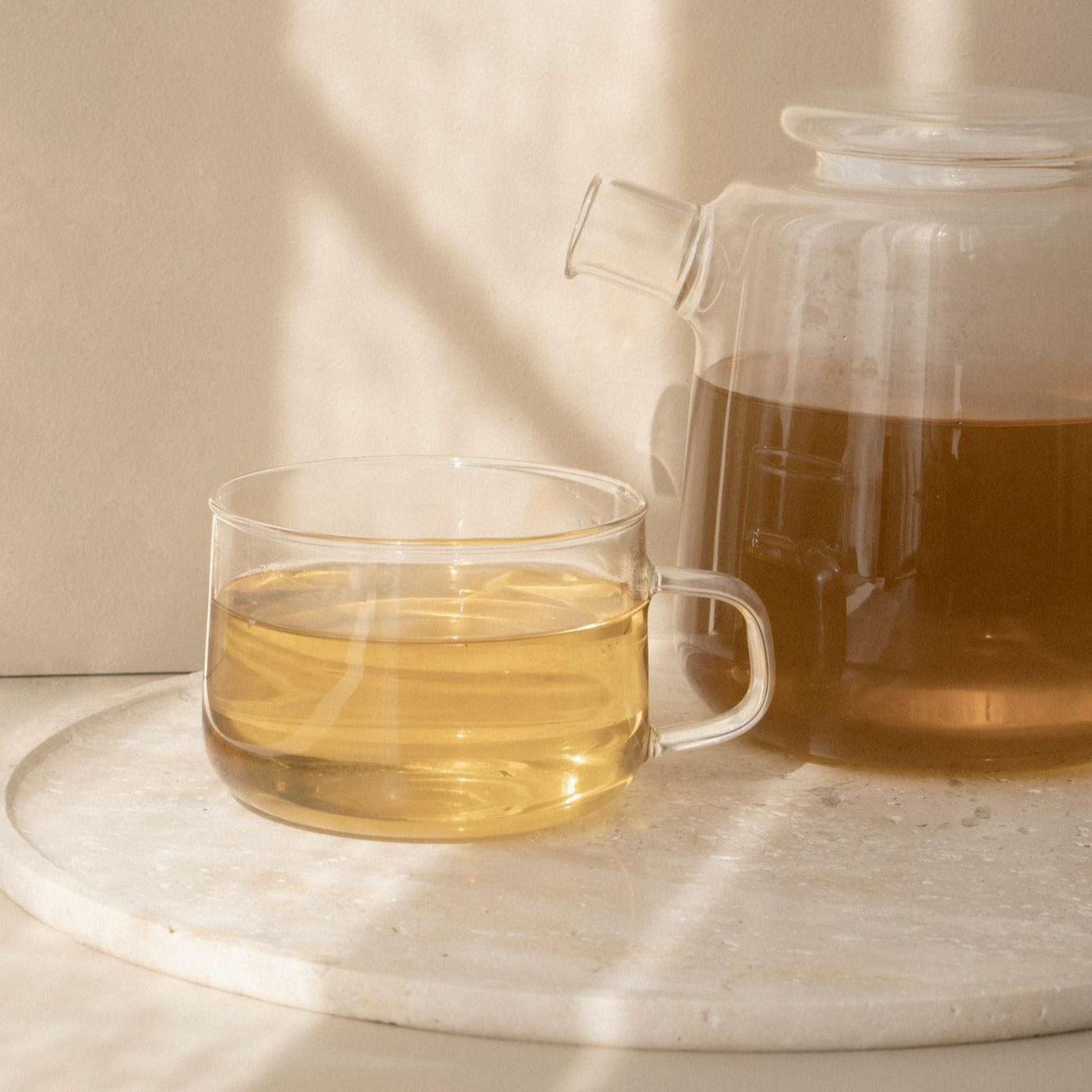 A postpartum nursing tea for breast massage accompanies green tea on a marble table.