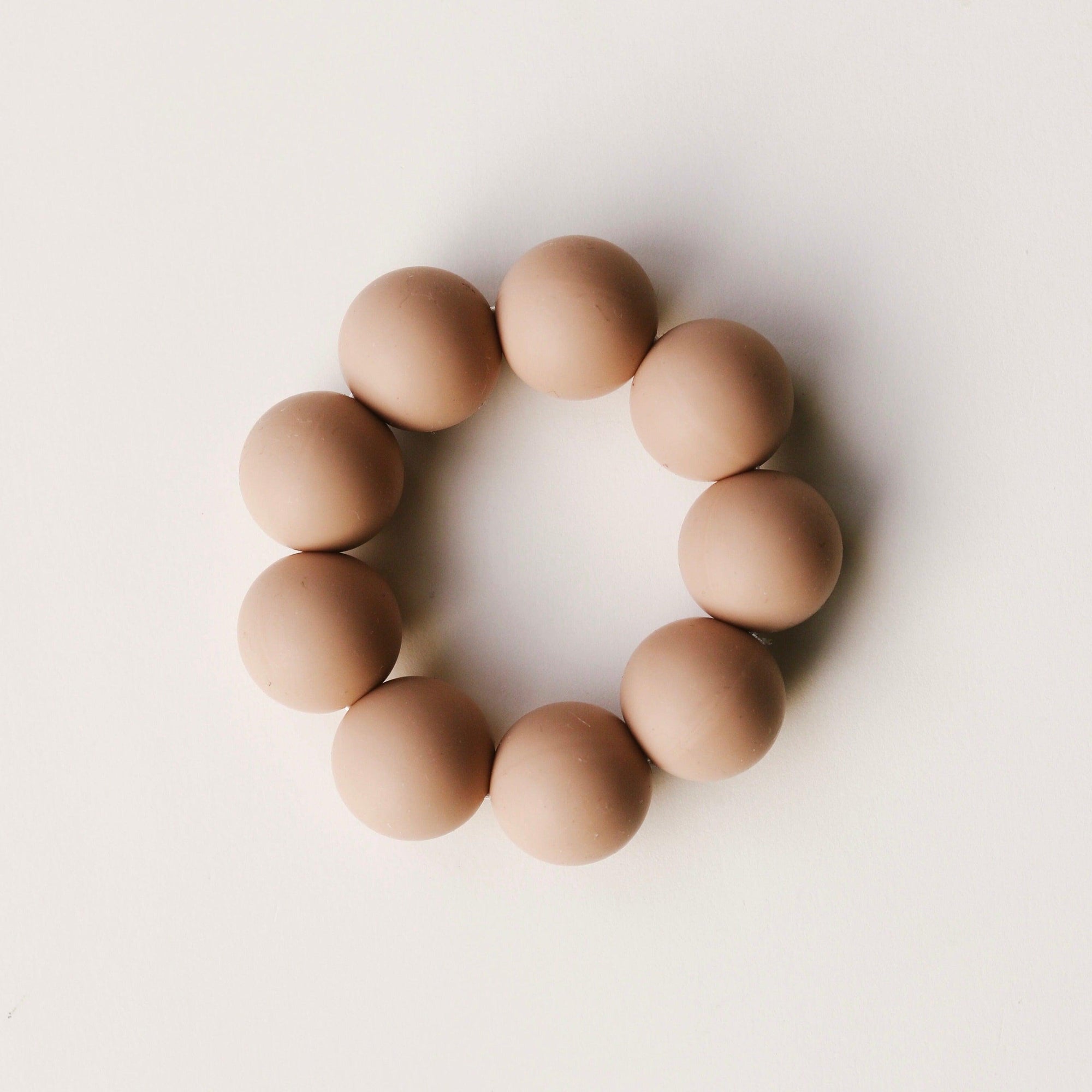 A Dove & Dovelet Silicone Teether in the shade Nude.