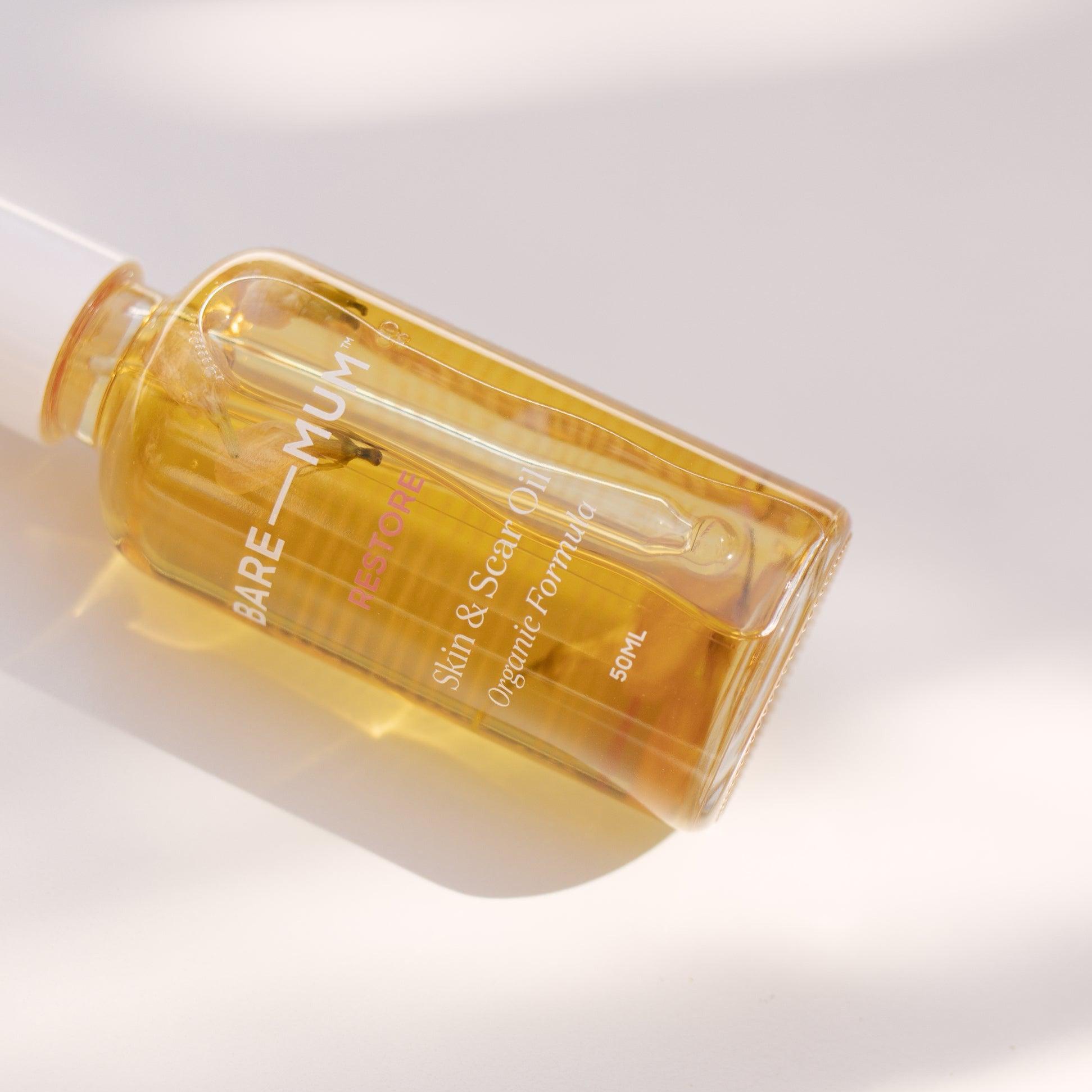 A bottle of Bare Mum's Skin & Scar Oil, commonly used by mothers during birth and breastfeeding, resting on a white surface.