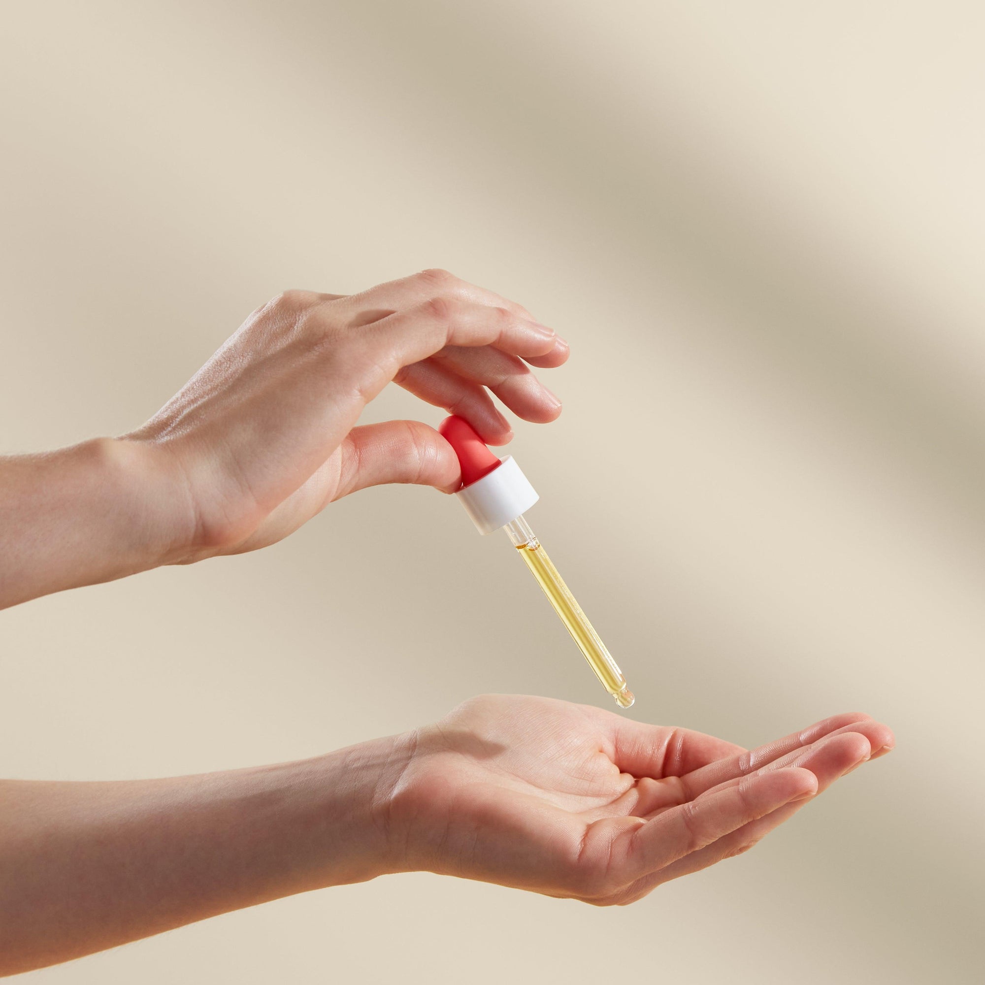 A mother's hand holding a bottle of Bare Mum Skin & Scar Oil.