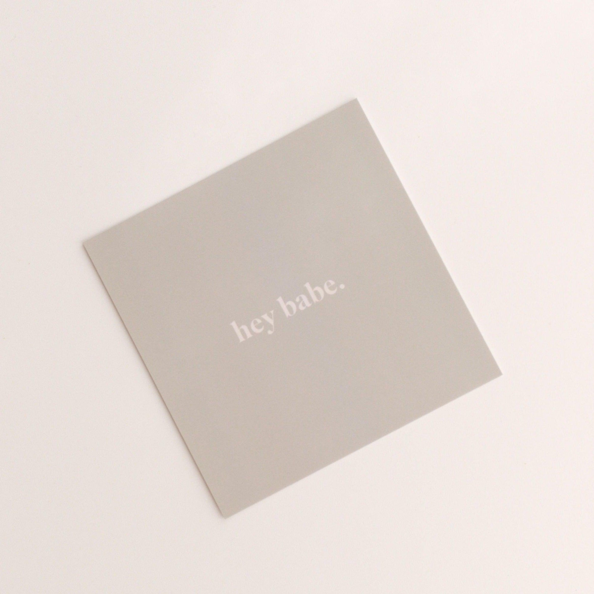 A square card from biglittlethings featuring the text "hey babe" on a plain background.