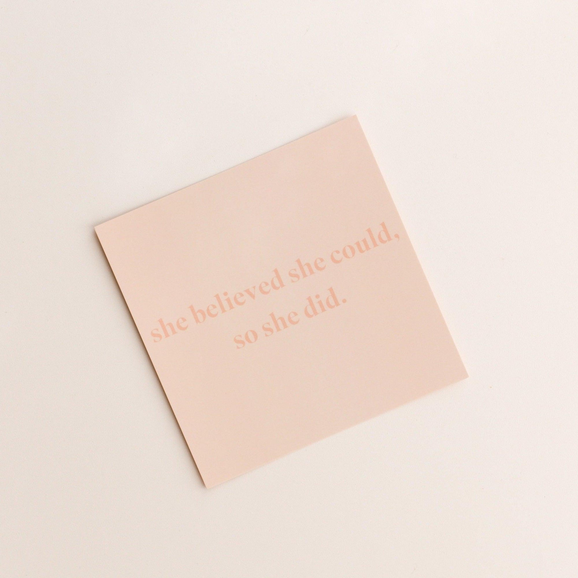 A beige square gift card from biglittlethings. featuring faint, pink text reading "she believed she could, so she did." on a plain white background.