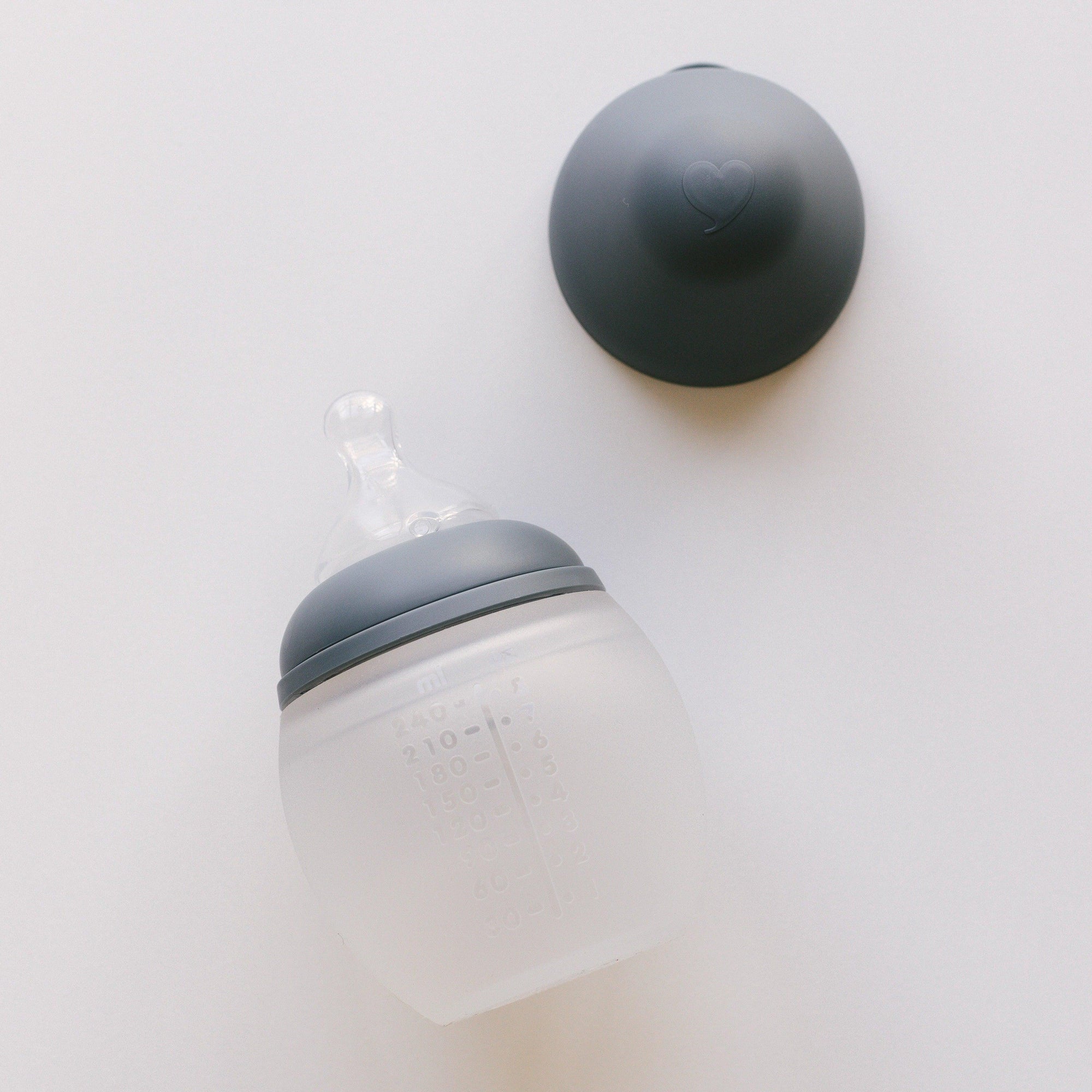 An Elhée France BibRond | blue grey baby bottle on a white surface.
