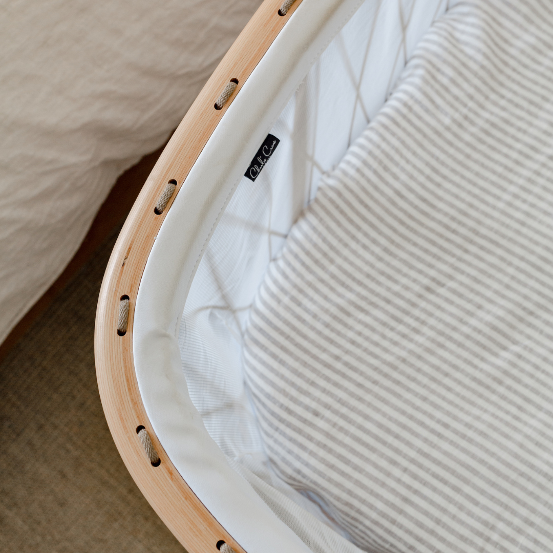 A close up of a Warren Hill crib with a wooden frame, in a neutral nursery.