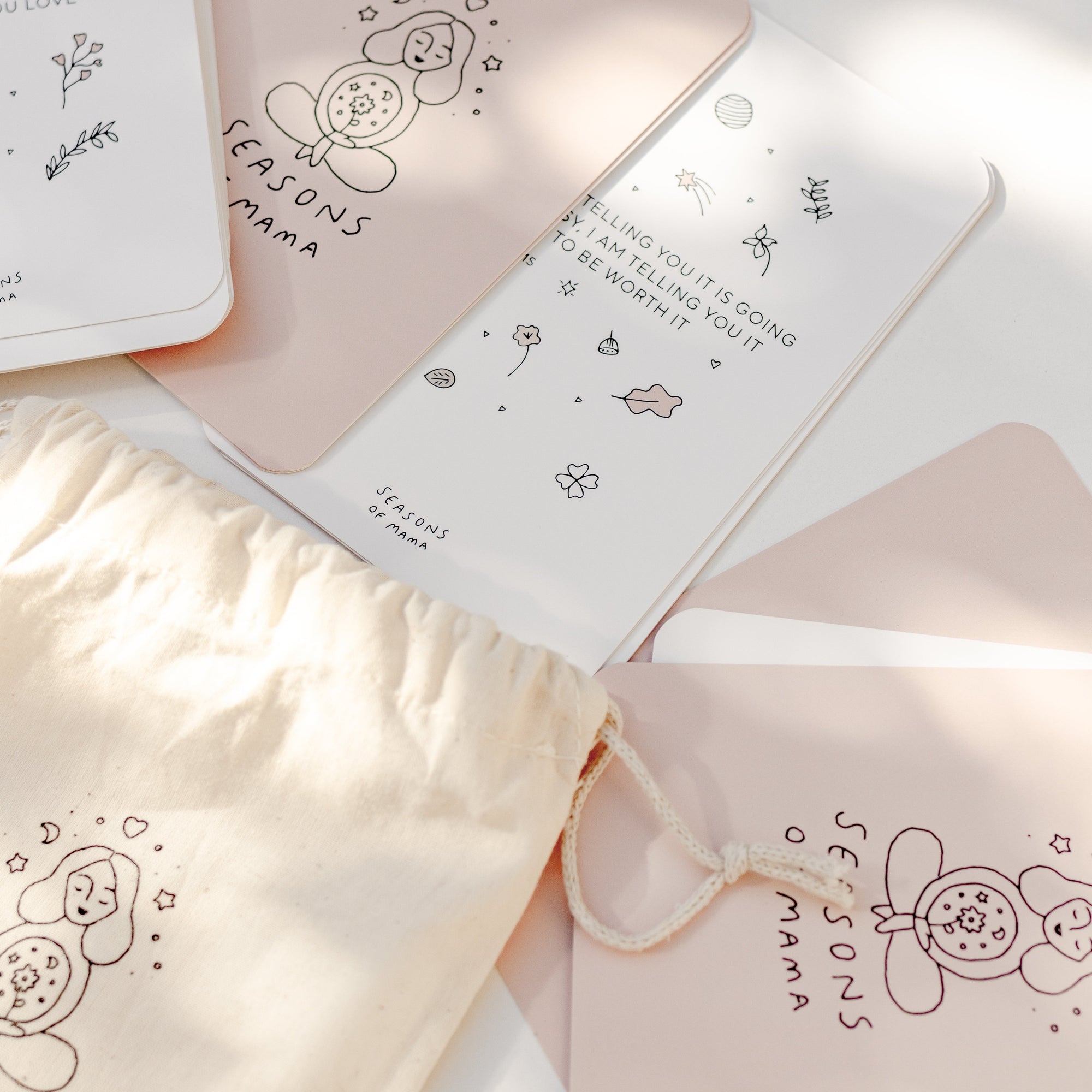 A branded calico bag featuring the Seasons of Mama Birth Affirmation Cards.