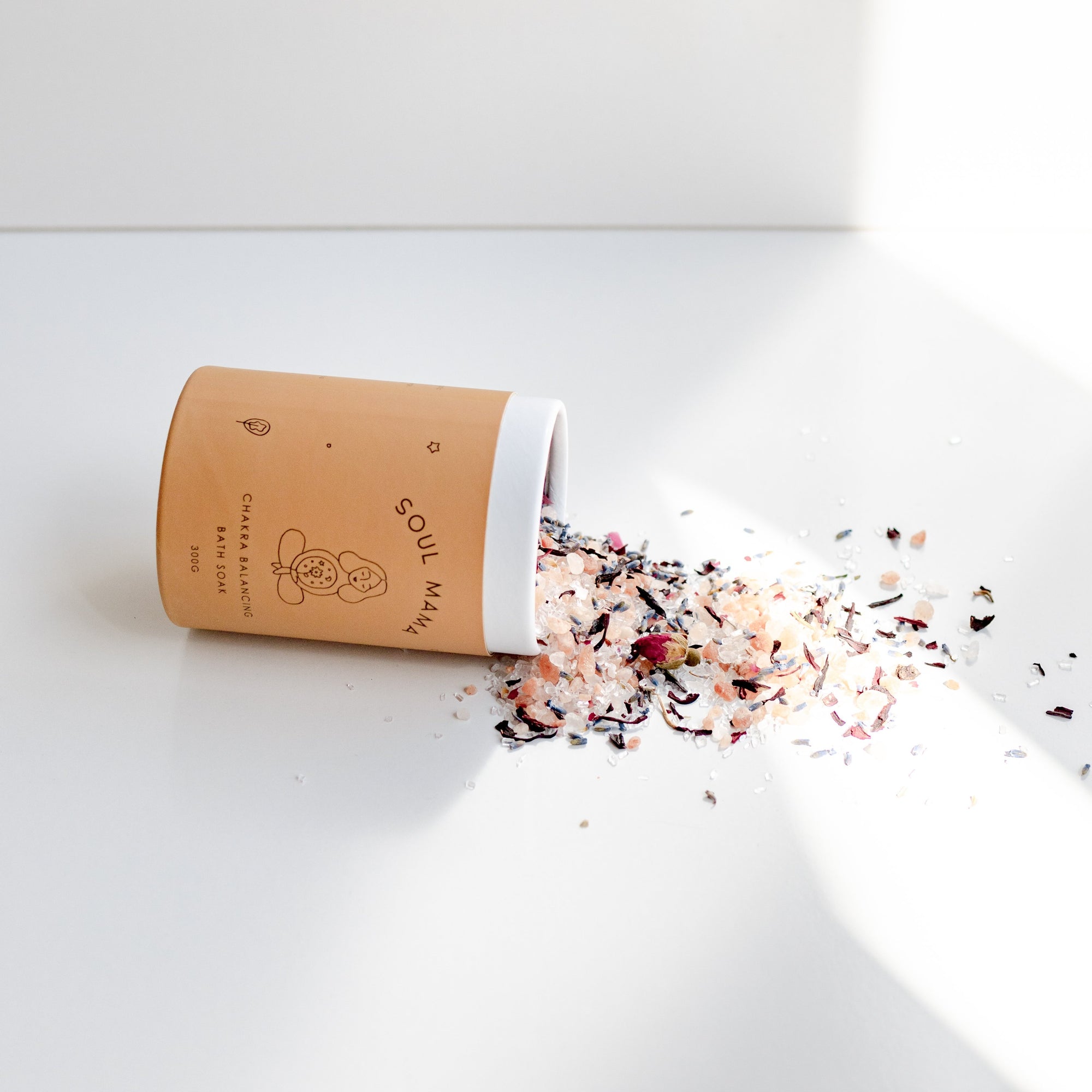 A jar of Seasons of Mama Soul Mama Chakra Balancing Bath Soak on a white bench.