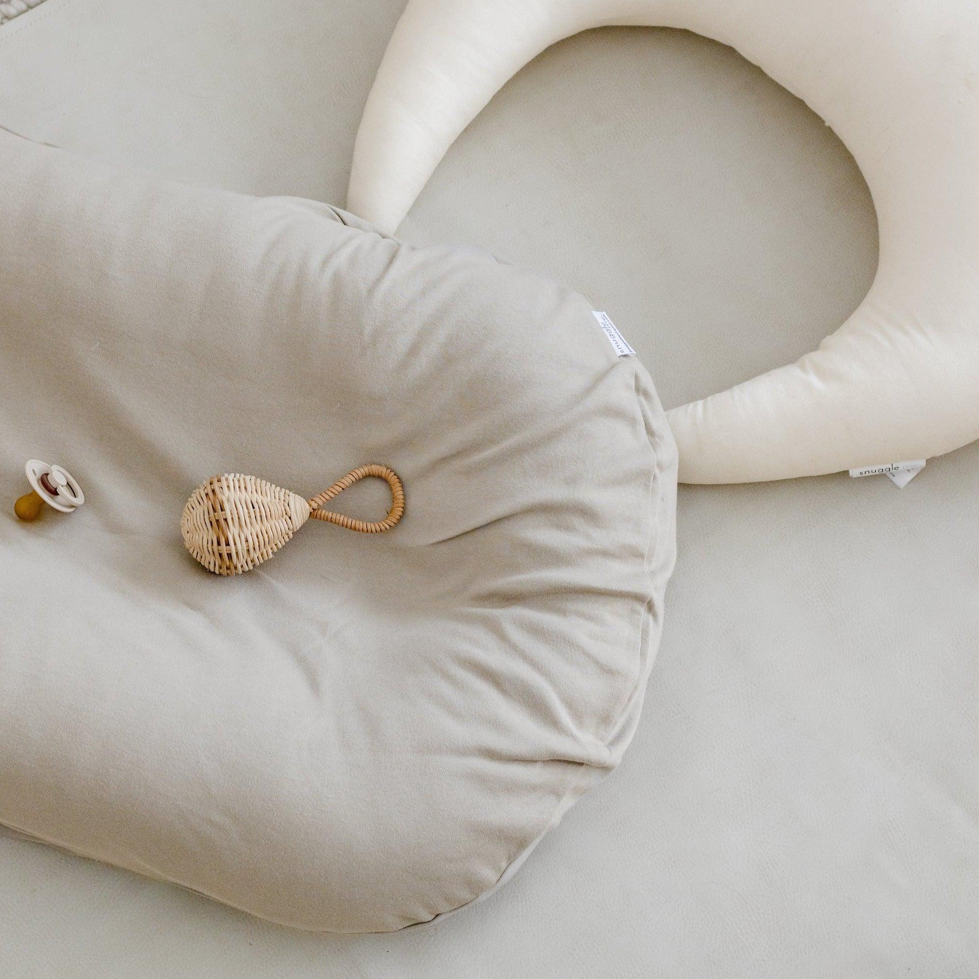 Snuggle Me Lounger Cover in the shade birch on a white surface next to a snuggle me pillow.