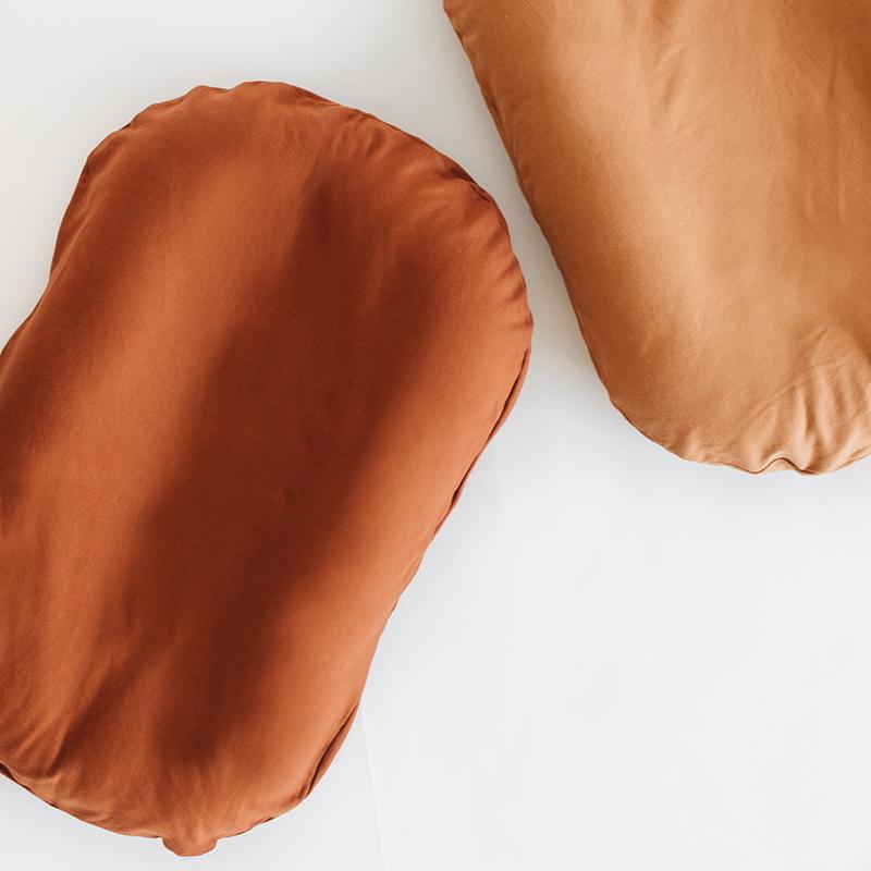 Two Snuggle Me Loungers with the lounger cover in the shade Gingerbread on a white surface.