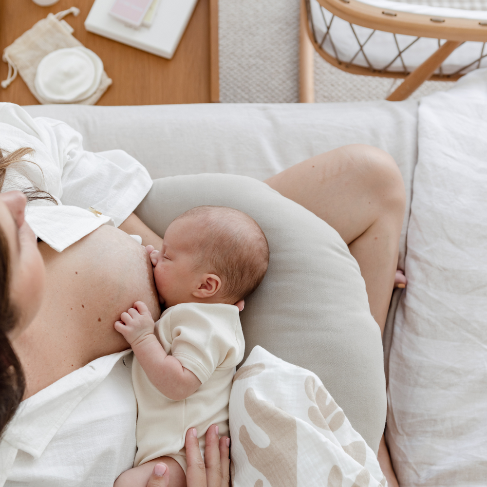 A birds eye view of a newborn breastfeeding, with breastfeeding products around the new mum.