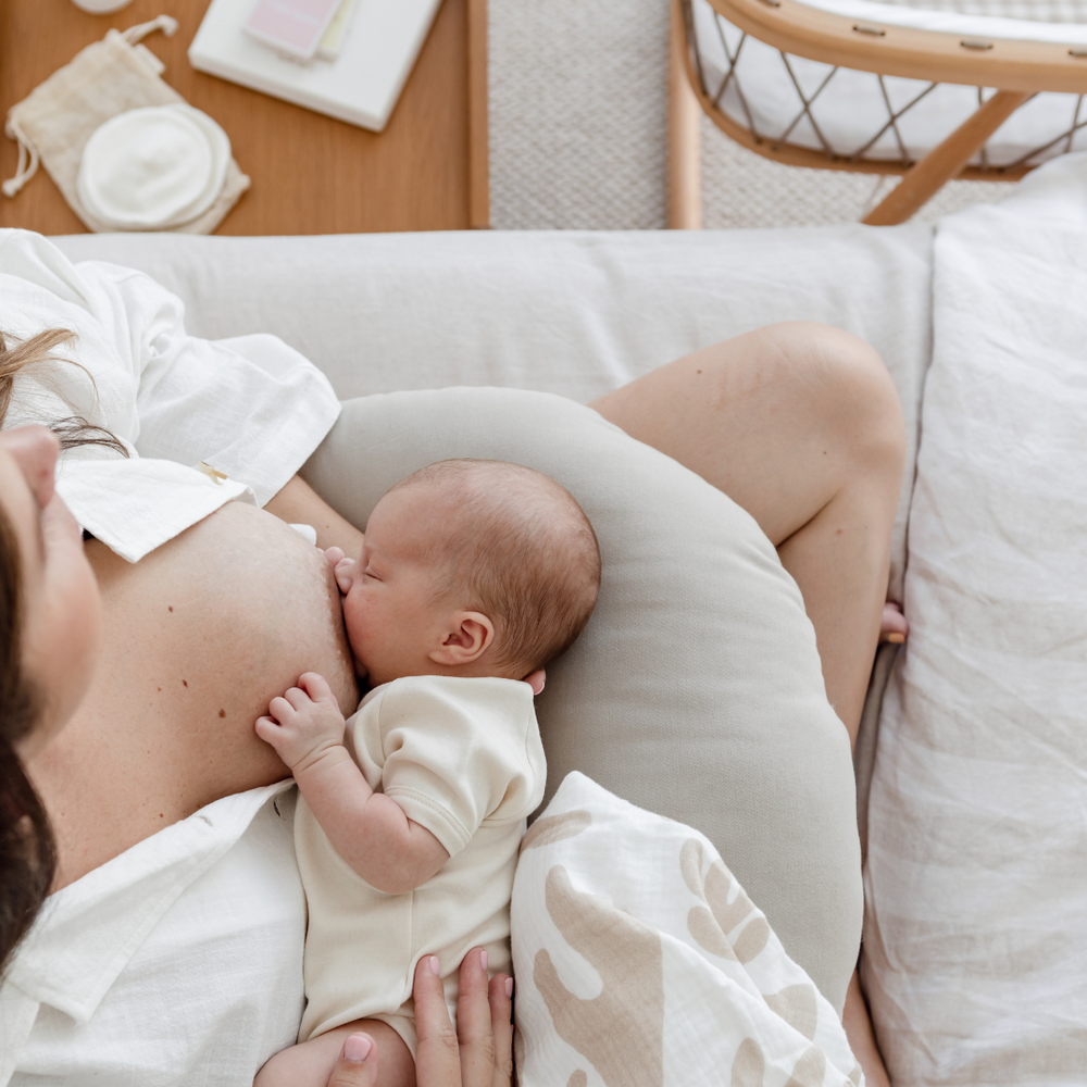 A birds eye view of a newborn breastfeeding, with breastfeeding products around the new mum. 