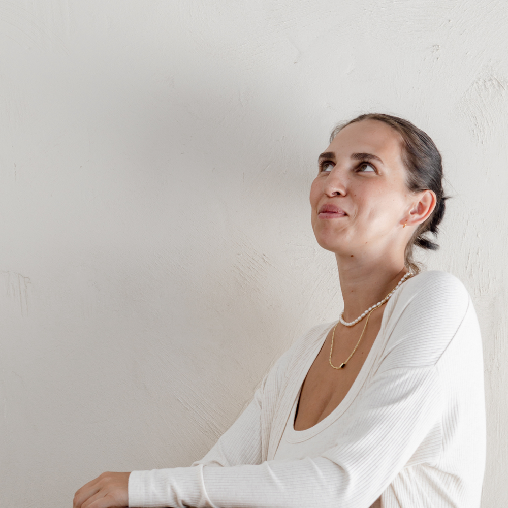 The top half of a new mum as she sits on the toilet and looks up into the corner of the photo. She could be contemplating going to the toilet for the first time after birth.