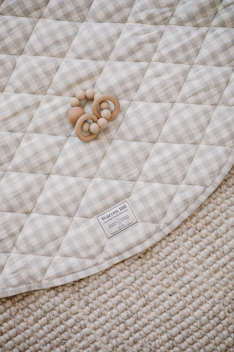 A baby's feet on a tan quilted mat.