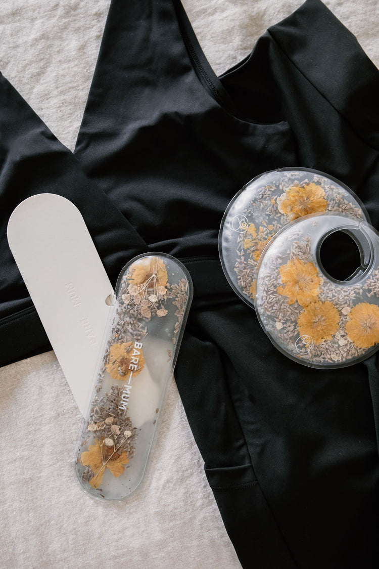 A pair of black leggings is displayed with two gel packs containing dried flowers and a white scraper-like tool.