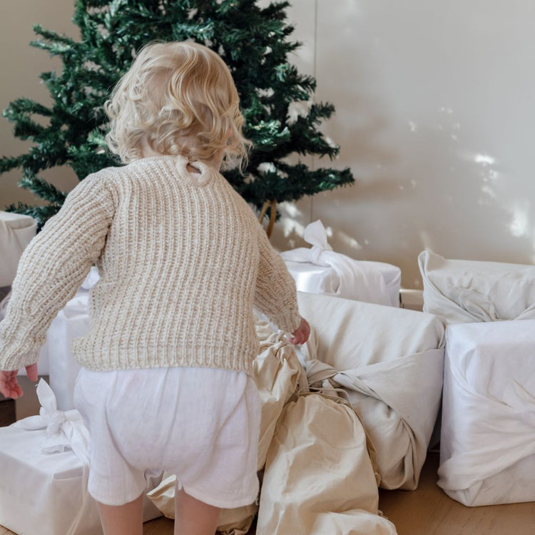 A little girl standing in front of a christmas tree.