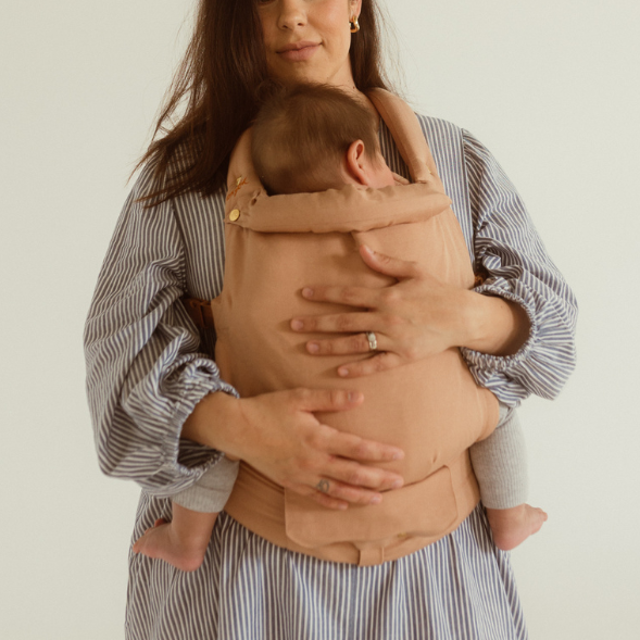 A woman cradling a baby in a Cinta Clip Carrier from Chekoh.