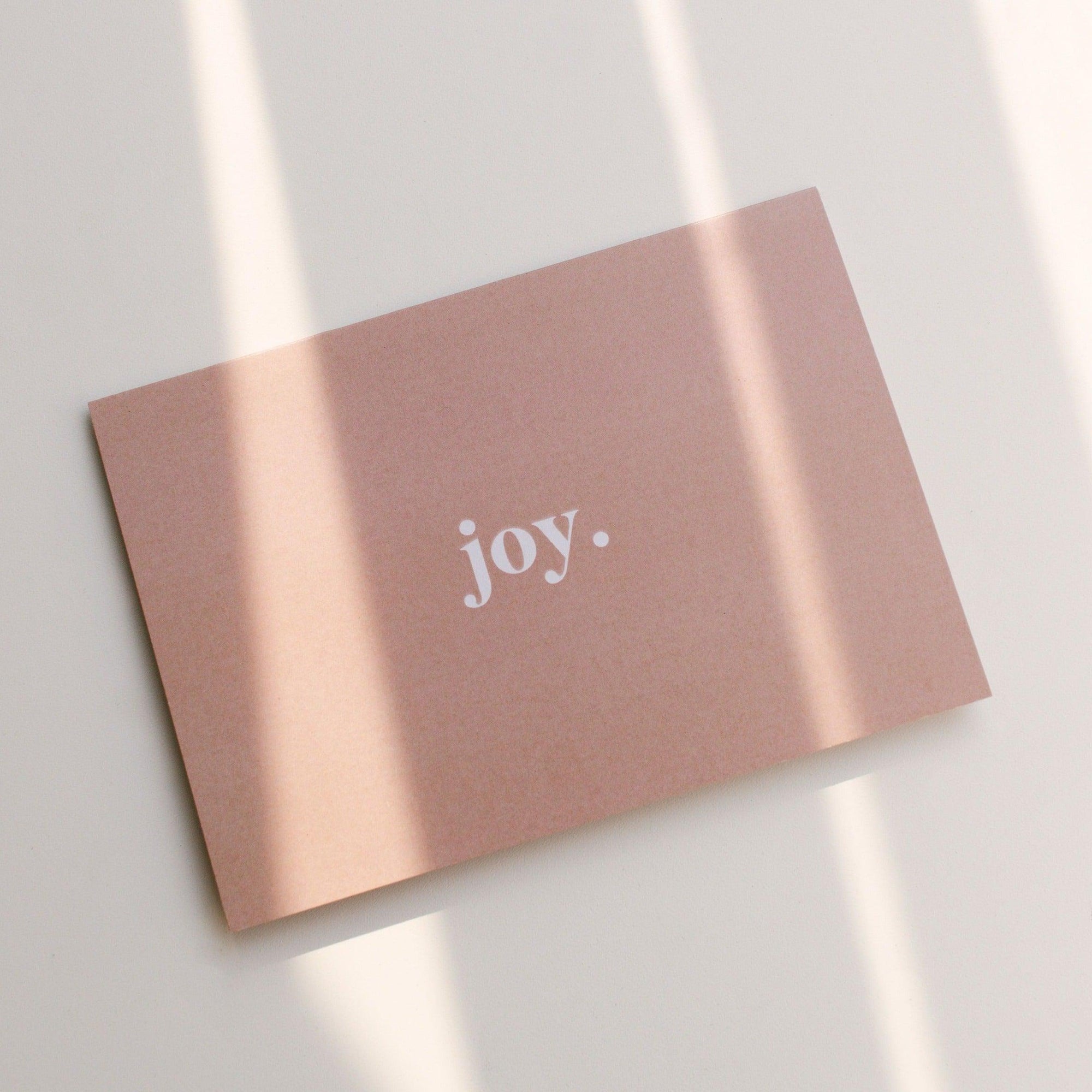 A pink card with the word joy on it, perfect for spreading happiness and positivity. Ideal as a biglittlethings gift voucher to bring a smile to your loved ones' faces.