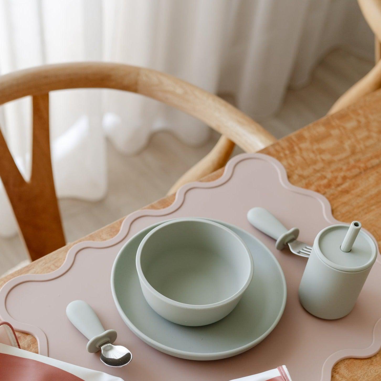 A table setting with a Rommer toddler cutlery set, including a plate, bowl, and spoon, designed to encourage independence during mealtime for curious little hands.