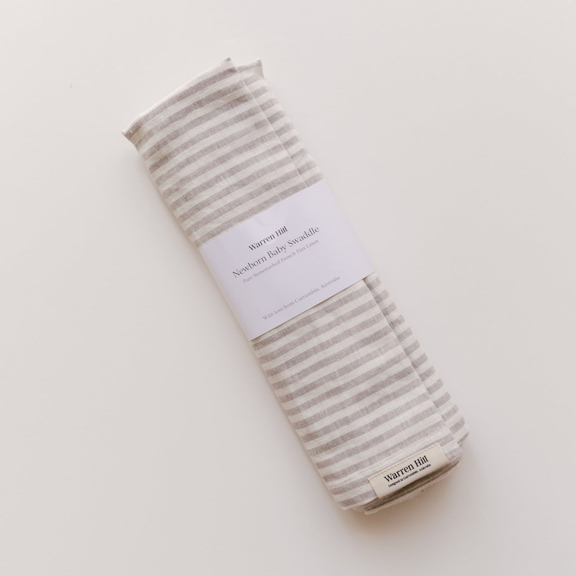 A Warren Hill french linen baby swaddle in grey stripe made of breathable stonewashed linen on a white surface.