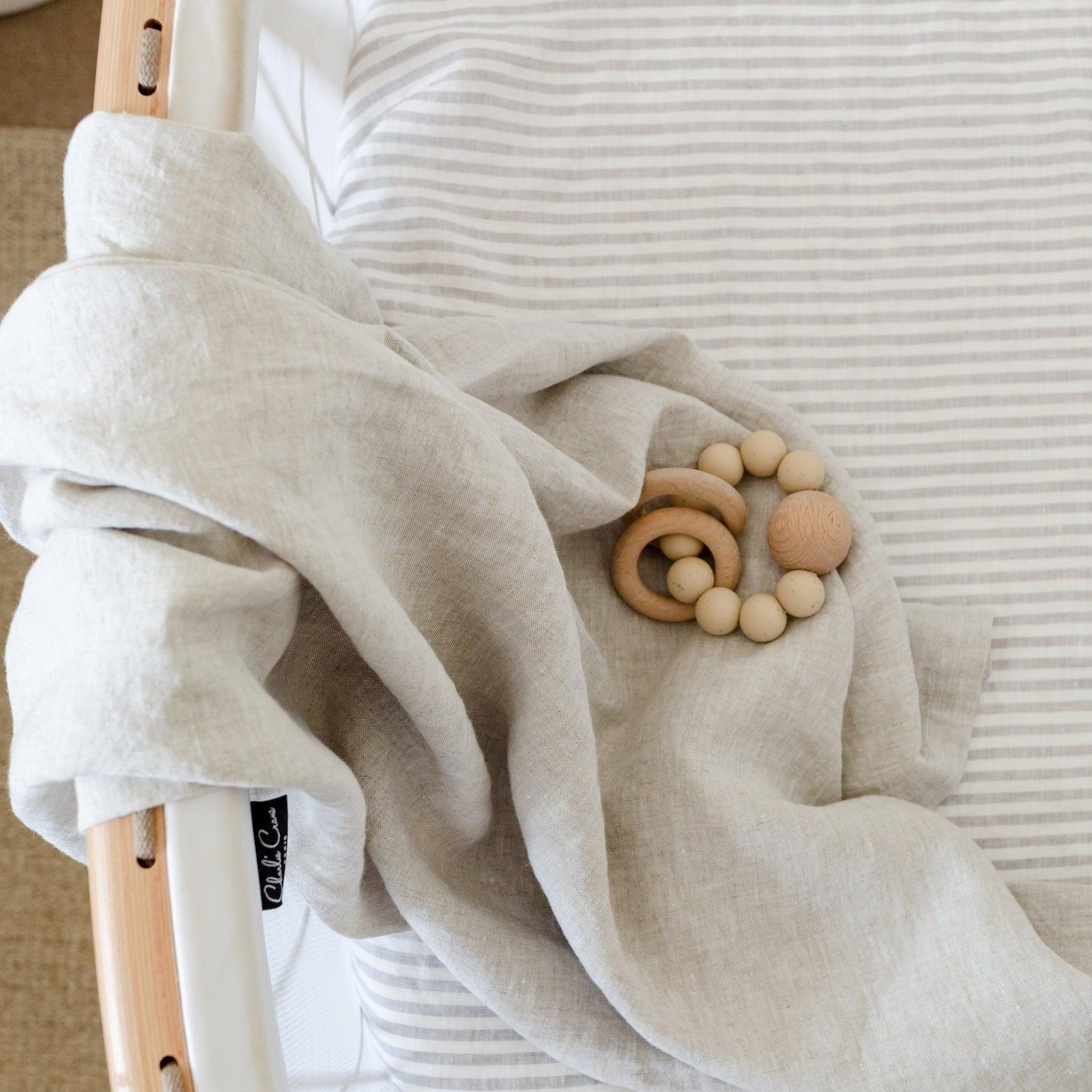 A baby's bed with a french linen baby swaddle made of breathable stonewashed linen from Warren Hill.