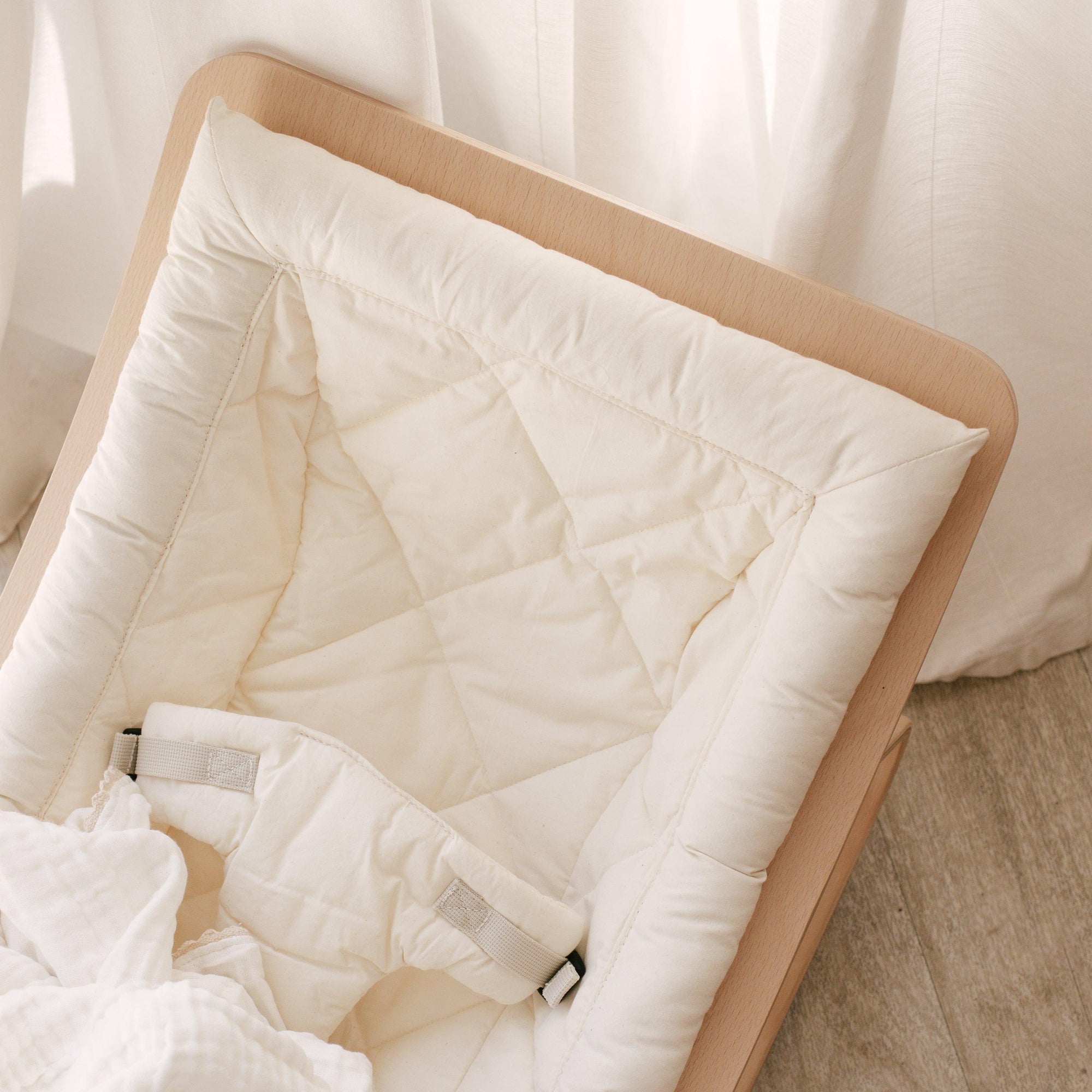 A Levo baby rocker in organic white with a blanket.