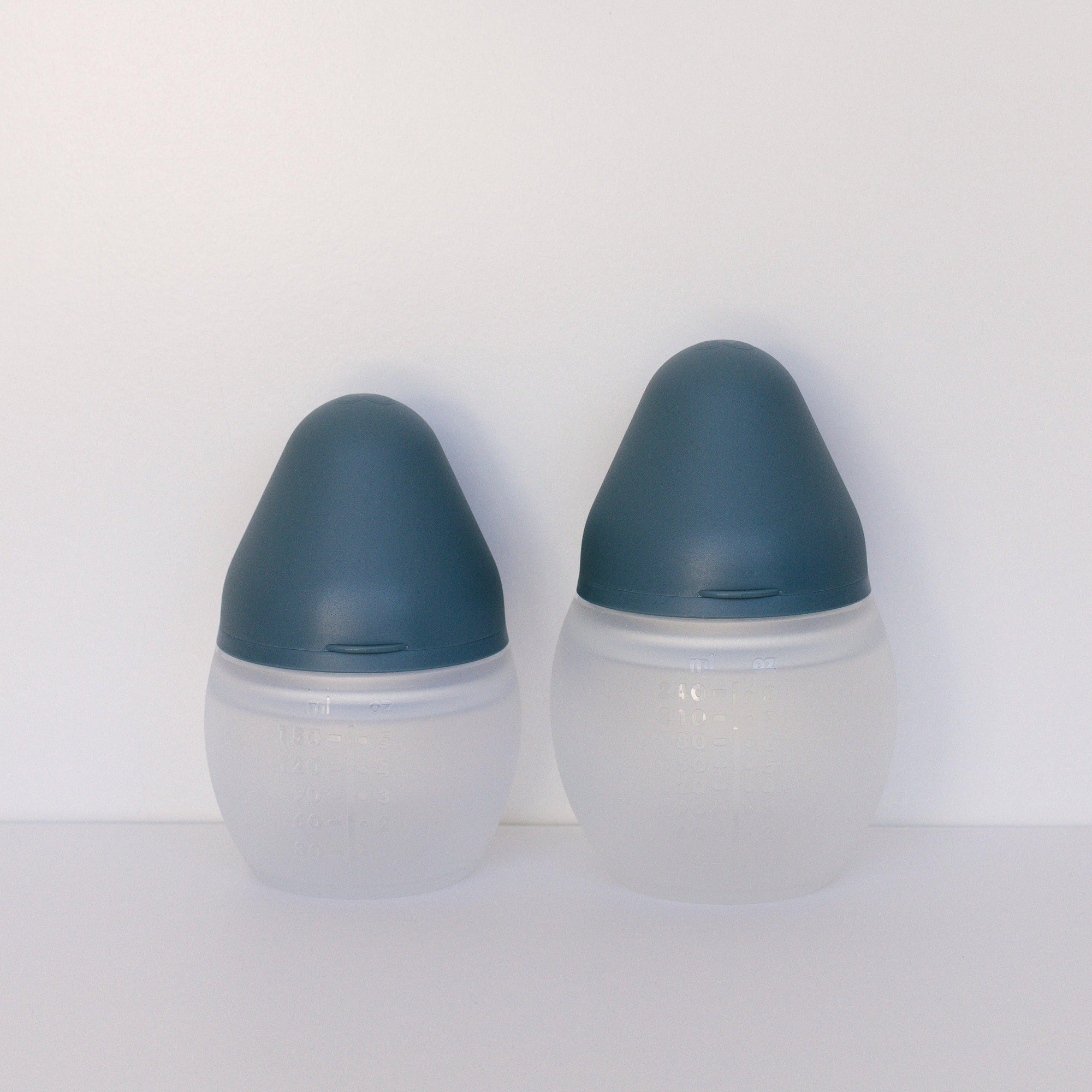 Two BibRond blue grey baby bottles by Elhée France sitting on a white surface.