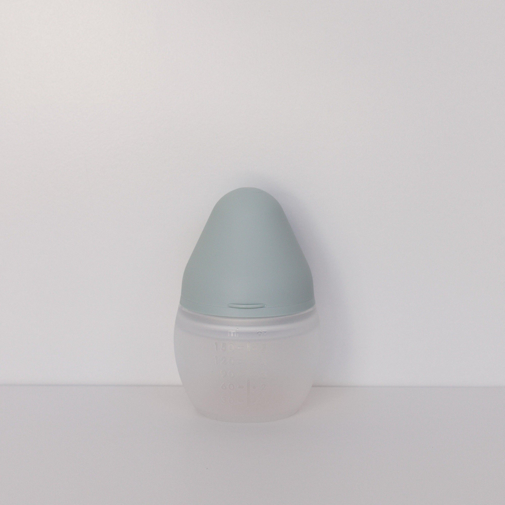 An Elhée France BibRond ivy green baby bottle sitting on a white surface.