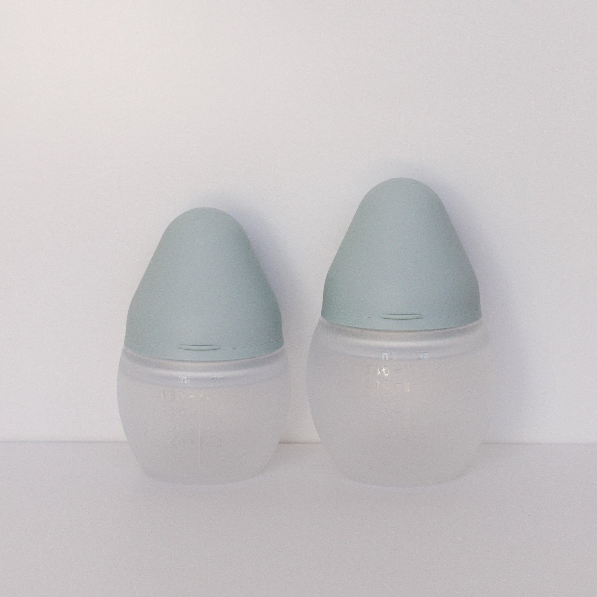 Two Elhée France BibRond ivy green baby bottles on a white surface.