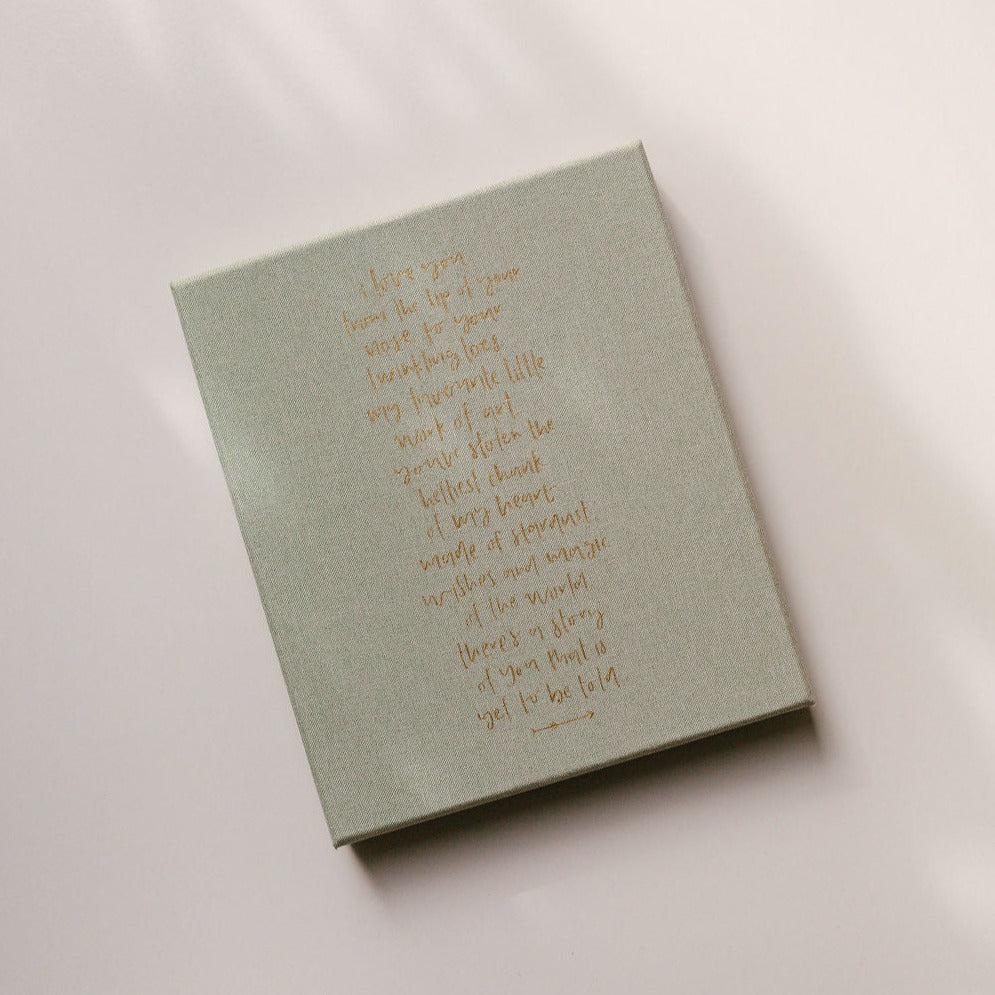 The back of the Emma Kate Co. Little Dreamer Baby Journal in sage featuring a quote in gold lettering.