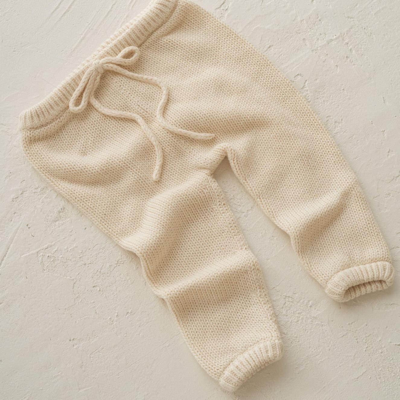 A baby's Illoura the Label "illoura poet pants | vanilla" on a white surface.