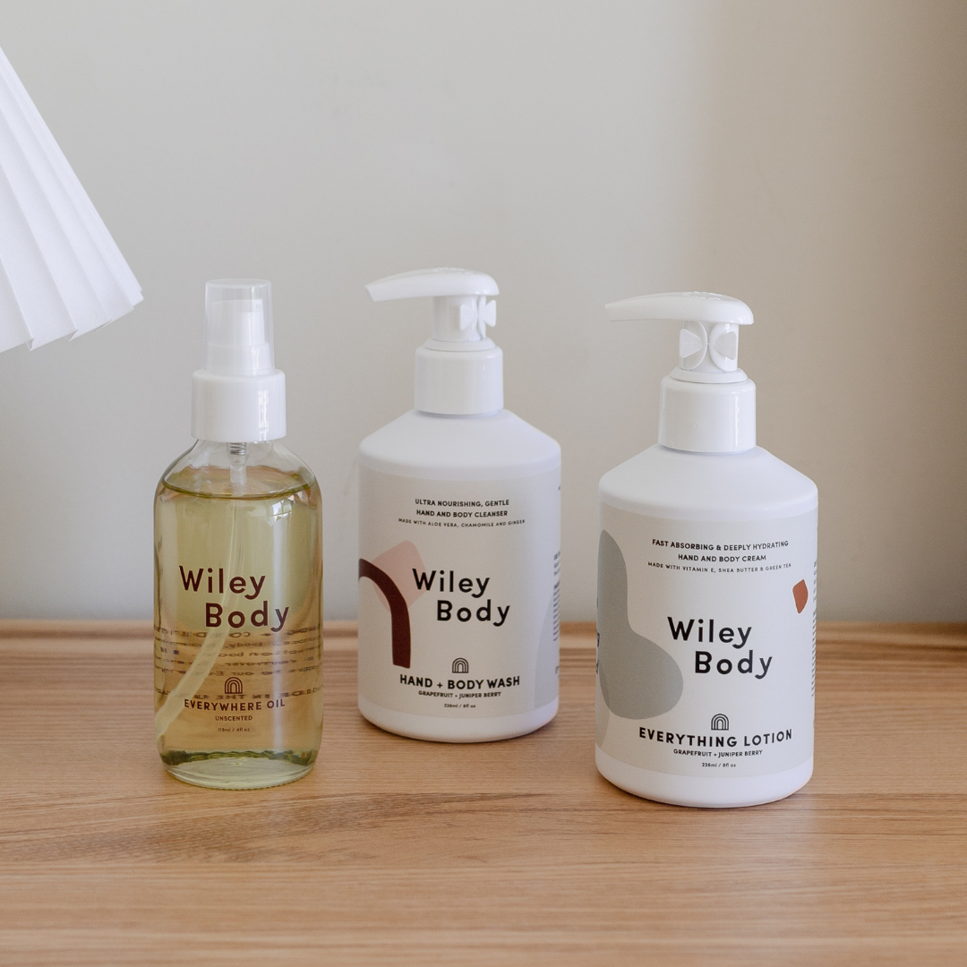 Three bottles of Wiley Body Bundle products, including the Hand & Body Wash from Wiley Body brand, displayed on a wooden table.