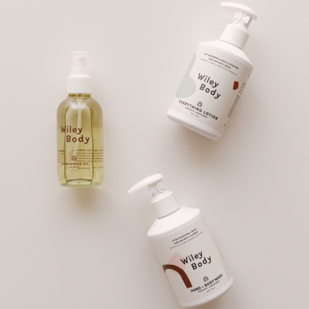 Three bottles of Wiley Body organic hand & body wash and lotion on a white surface.